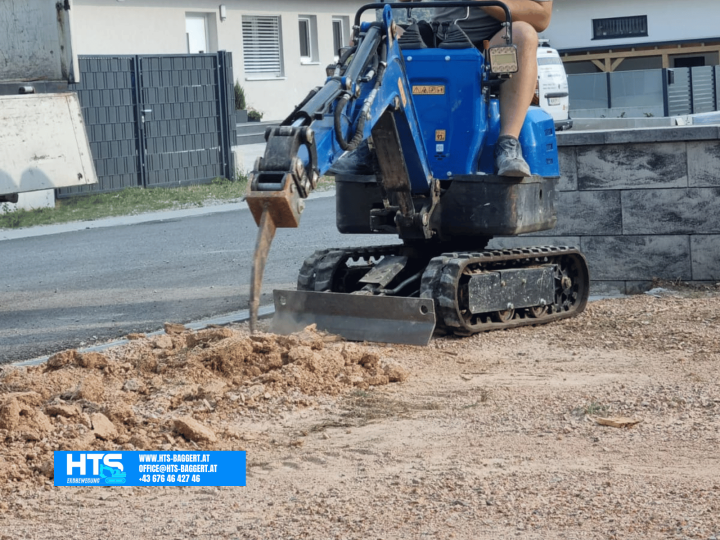 Kompakter Minibagger beim Lockern eines nahezu betonhart verdichteten Pflasterunterbaus mit dem Reißzahn
