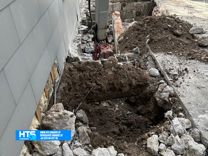 Minibagger bei Erdarbeiten im freigelegten Bereich entlang der Hauswand zur Vorbereitung der weiteren Trockenlegungs und Drainagearbeiten.